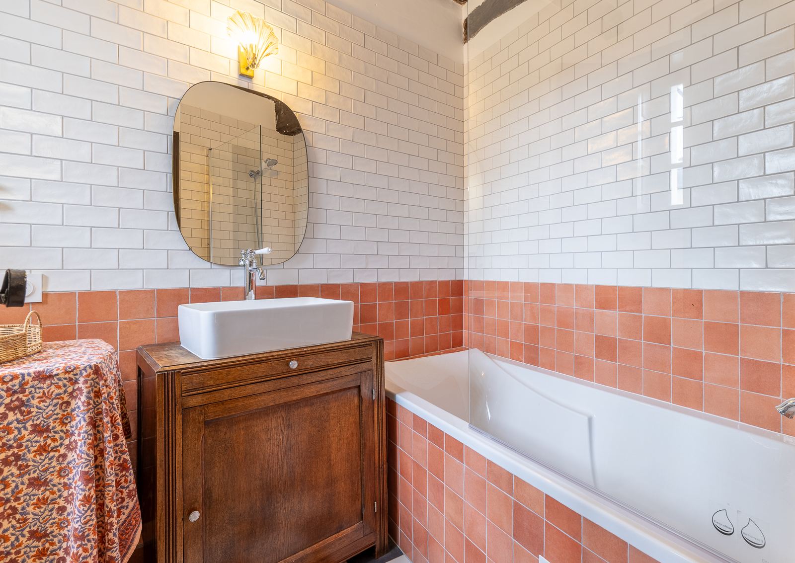 Salle de bain avec baignoire, carrelage métro blanc et terracotta, meuble vasque ancien