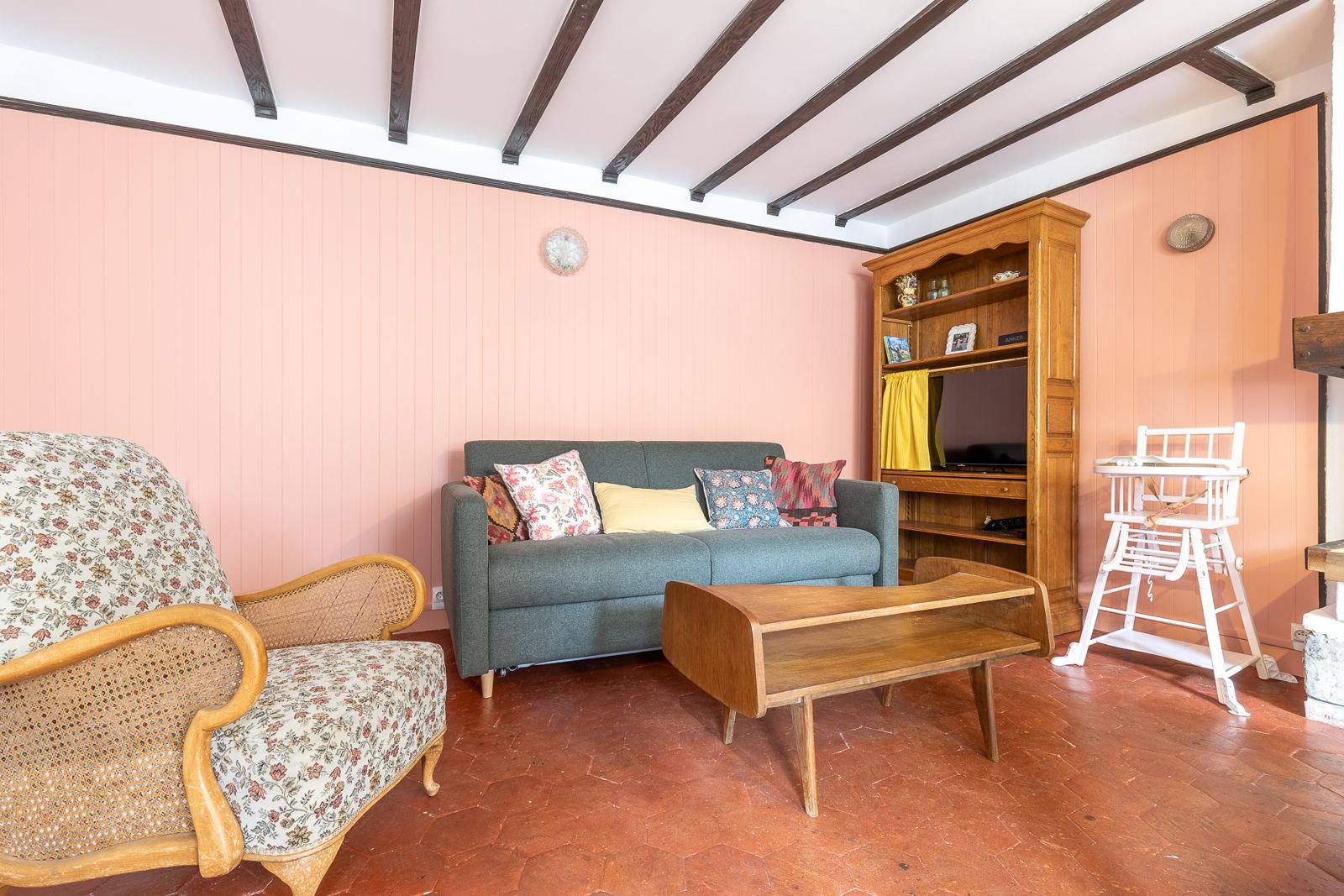 Le salon : lambris rose, canapé, table basse vintage et chaise haute